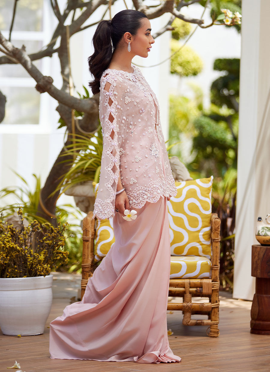 Effortless grace meets artistic craftsmanship in this straight long shirt ensemble. Delicately scattered across the fabric, floral motifs are rendered in intricate embroidery designed to mimic the softness and nuance of pencil colour shading. These artistic blooms are further elevated with delicate silver hand-work and subtle self-colored sequins, creating a harmonious blend of texture and light. The neckline and collar are trimmed with a scalloped border, hand-embellished with classic mukesh work, adding a