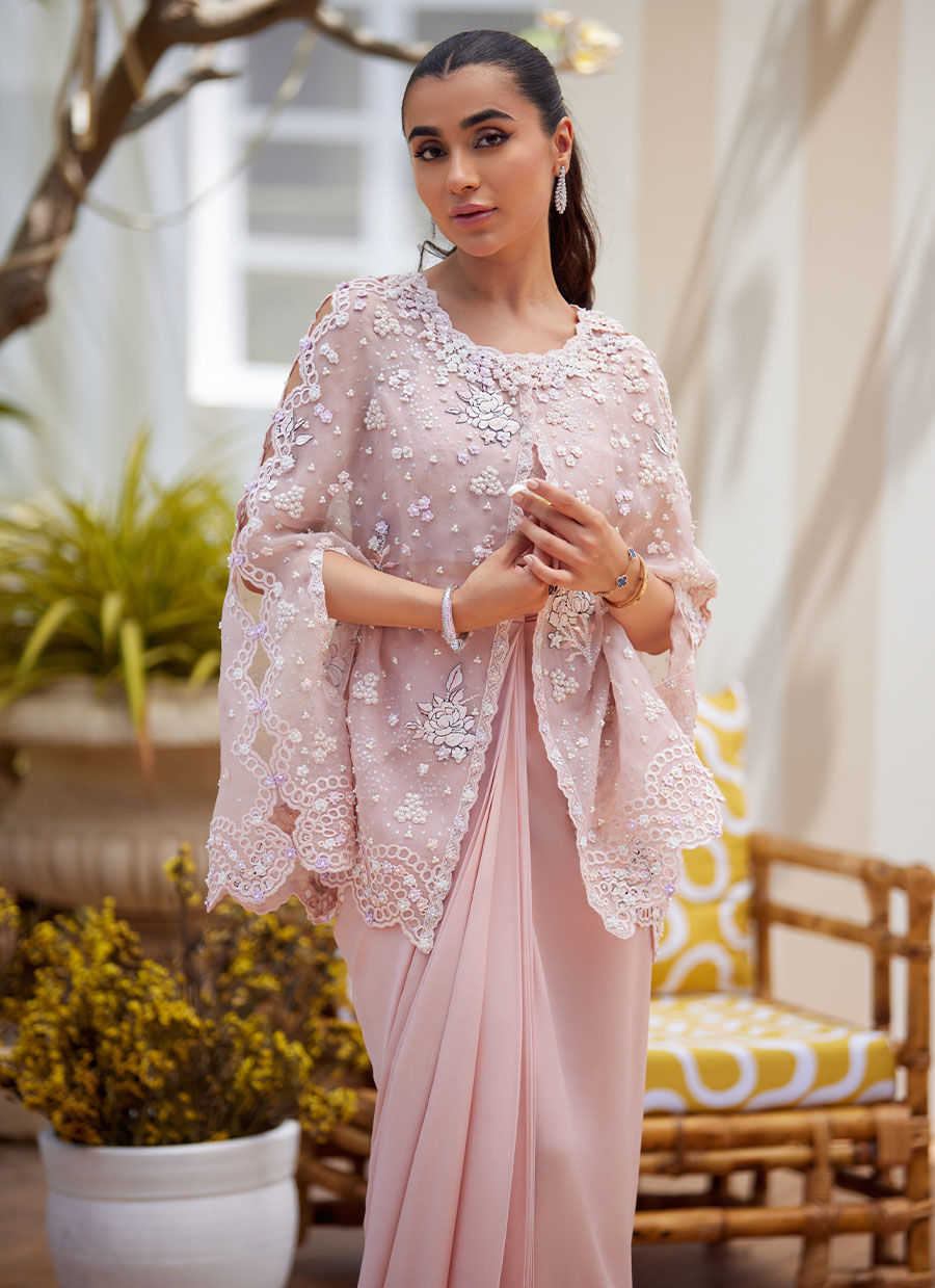 Effortless grace meets artistic craftsmanship in this straight long shirt ensemble. Delicately scattered across the fabric, floral motifs are rendered in intricate embroidery designed to mimic the softness and nuance of pencil colour shading. These artistic blooms are further elevated with delicate silver hand-work and subtle self-colored sequins, creating a harmonious blend of texture and light. The neckline and collar are trimmed with a scalloped border, hand-embellished with classic mukesh work, adding a