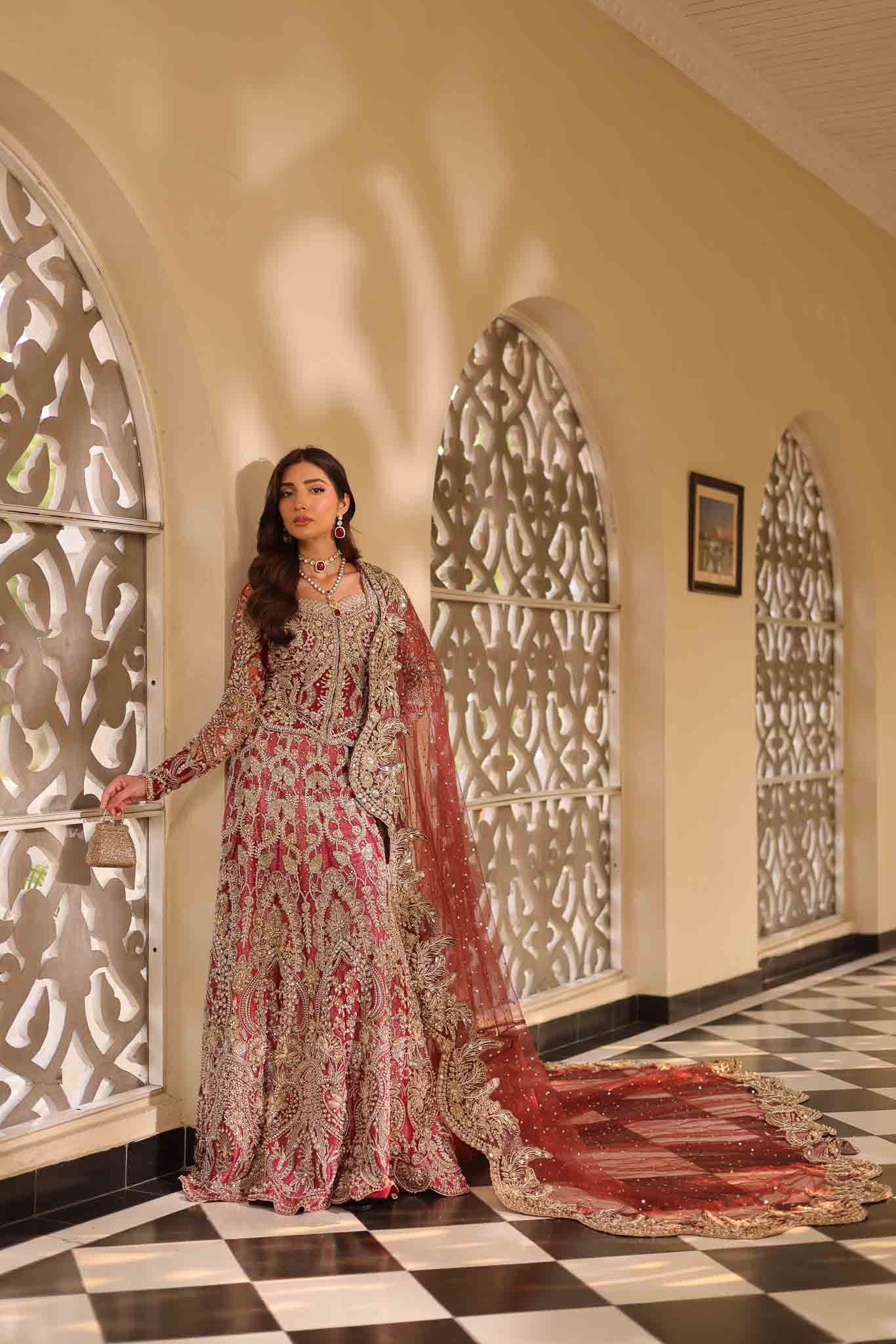 Model wearing deep red and gold bridal gown AURAA from Mysie by Tahira, Pakistani luxury pret available online in UK for weddings.