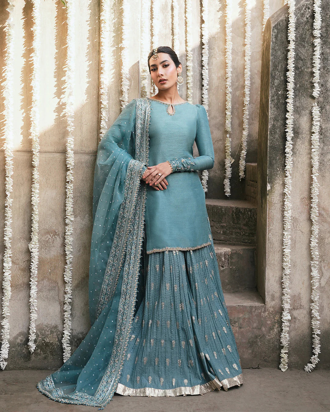Model wearing teal blue Faiza Saqlain Tisha outfit with embellished dupatta and gharara, perfect for Pakistani luxury pret in UK.