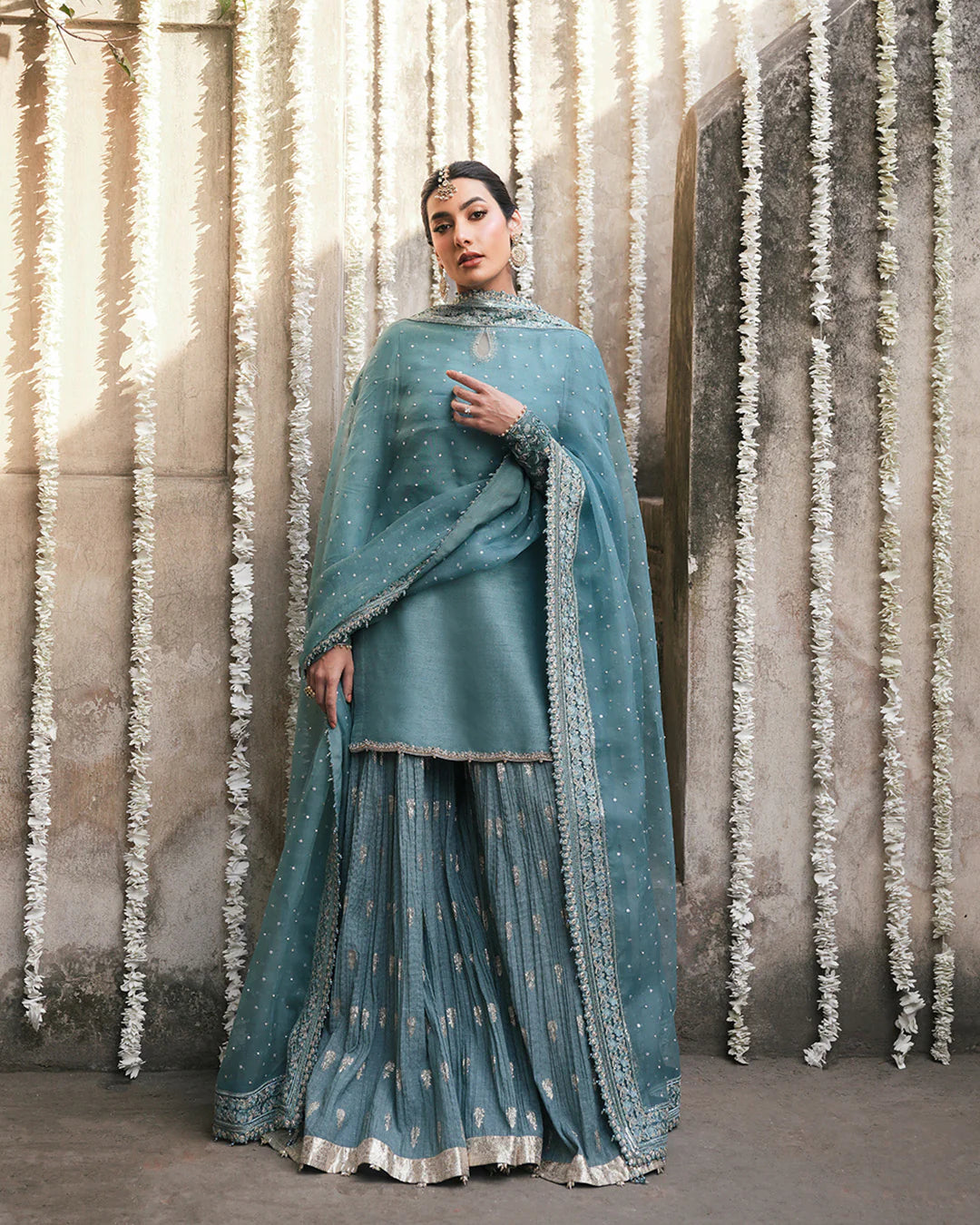 Model wearing teal blue Faiza Saqlain Tisha outfit with embellished dupatta and gharara, perfect for Pakistani luxury pret in UK.