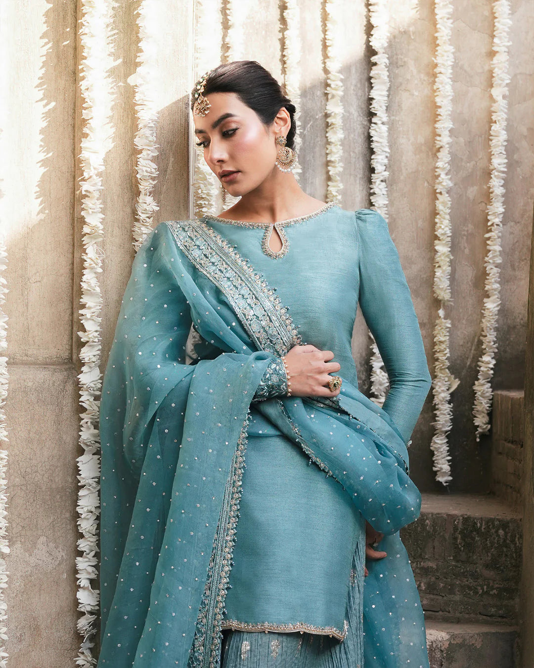 Model wearing teal blue Faiza Saqlain Tisha outfit with embellished dupatta and gharara, perfect for Pakistani luxury pret in UK.