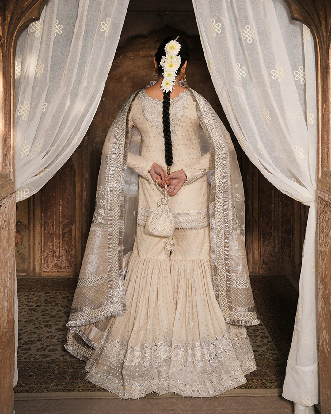 Model wearing ivory Faiza Saqlain Devina outfit with embellished gharara and dupatta, ideal for Pakistani luxury pret and festive wear in UK.