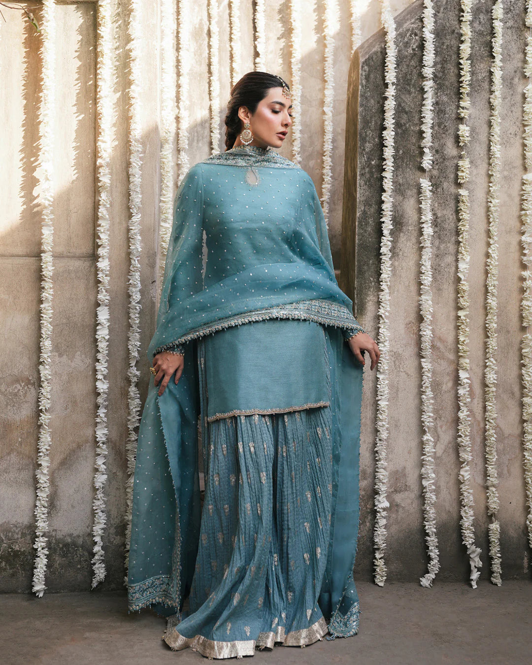 Model wearing teal blue Faiza Saqlain Tisha outfit with embellished dupatta and gharara, perfect for Pakistani luxury pret in UK.