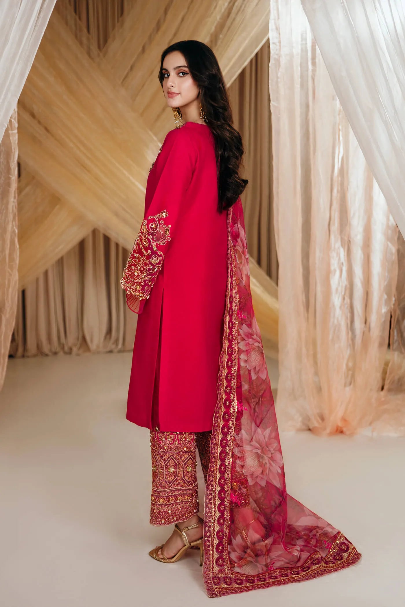 Model wearing Faiza Saqlain's Radiant Bloom dress from the Musferah Saad Mystere Eid Collection '24. A striking magenta Pakistani Eid dress with detailed gold embroidery and a floral dupatta, perfect for those seeking Pakistani designer clothes in the UK.