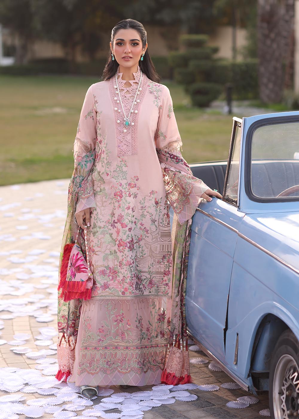 Model wearing pastel pink floral printed dress with lace neckline and embroidered dupatta from Musferah Saad Pretty Girls Luxury Lawn 2025 Bloome. Pakistani clothes online UK.