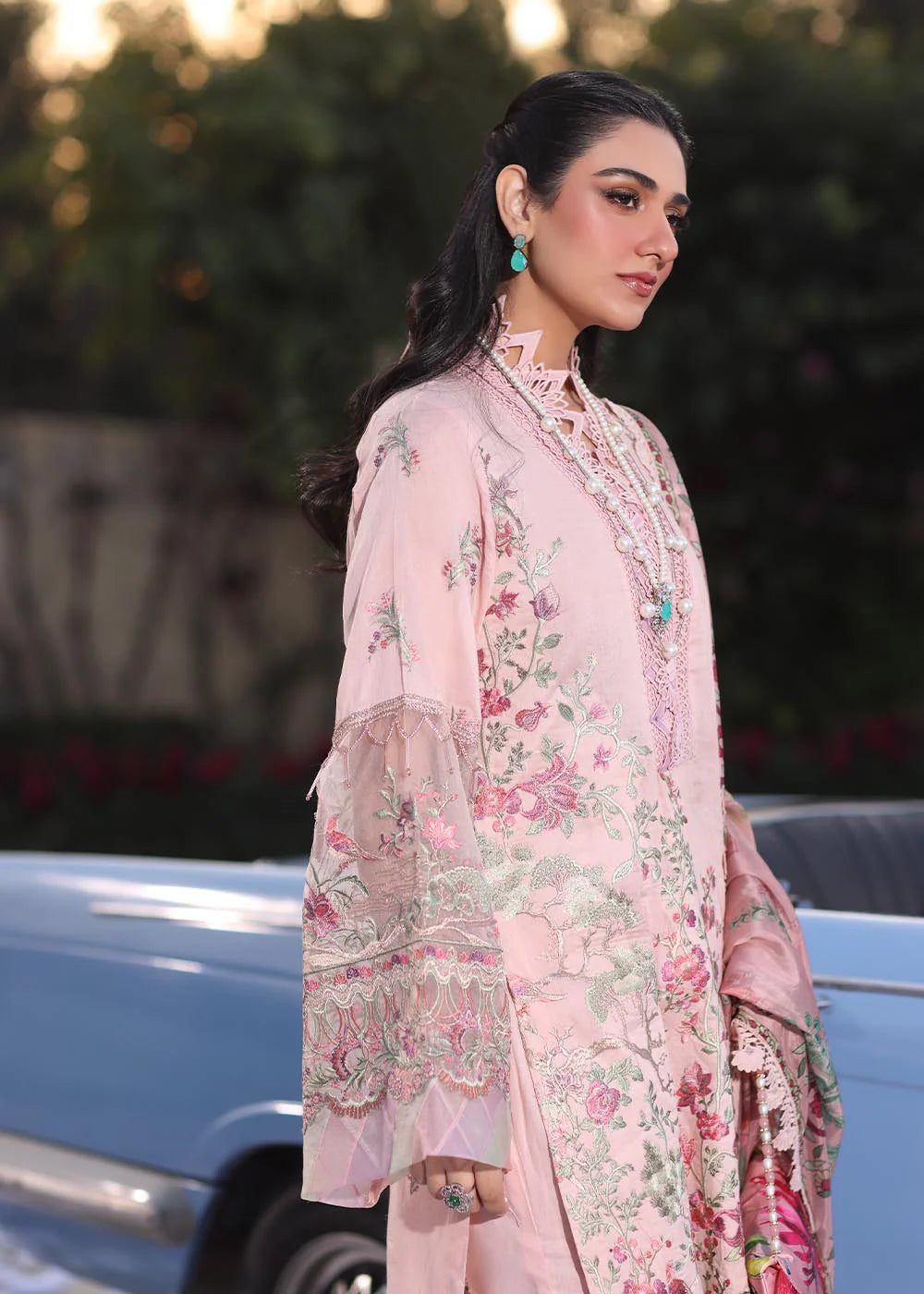 Model wearing pastel pink floral printed dress with lace neckline and embroidered dupatta from Musferah Saad Pretty Girls Luxury Lawn 2025 Bloome. Pakistani clothes online UK.