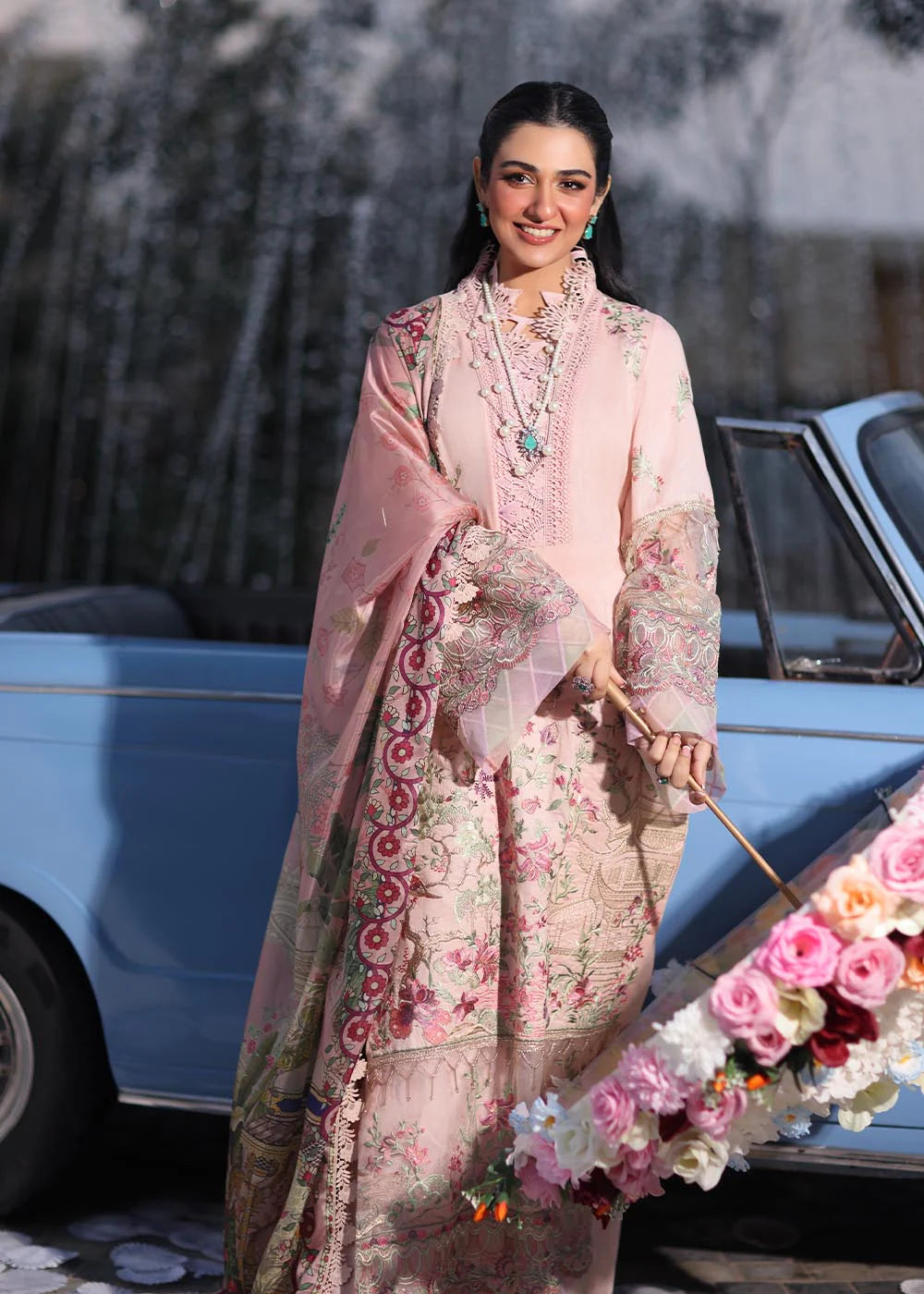 Model wearing pastel pink floral printed dress with lace neckline and embroidered dupatta from Musferah Saad Pretty Girls Luxury Lawn 2025 Bloome. Pakistani clothes online UK.