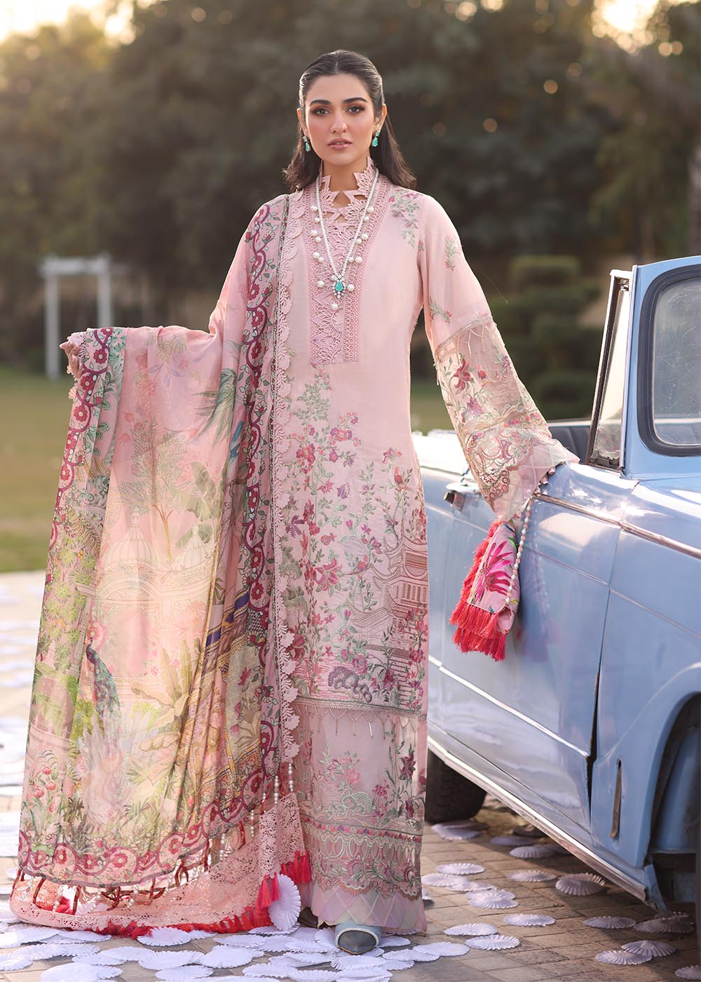 Model wearing pastel pink floral printed dress with lace neckline and embroidered dupatta from Musferah Saad Pretty Girls Luxury Lawn 2025 Bloome. Pakistani clothes online UK.