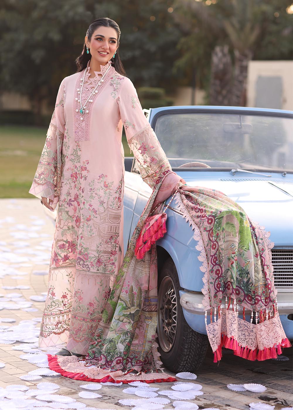 Model wearing pastel pink floral printed dress with lace neckline and embroidered dupatta from Musferah Saad Pretty Girls Luxury Lawn 2025 Bloome. Pakistani clothes online UK.