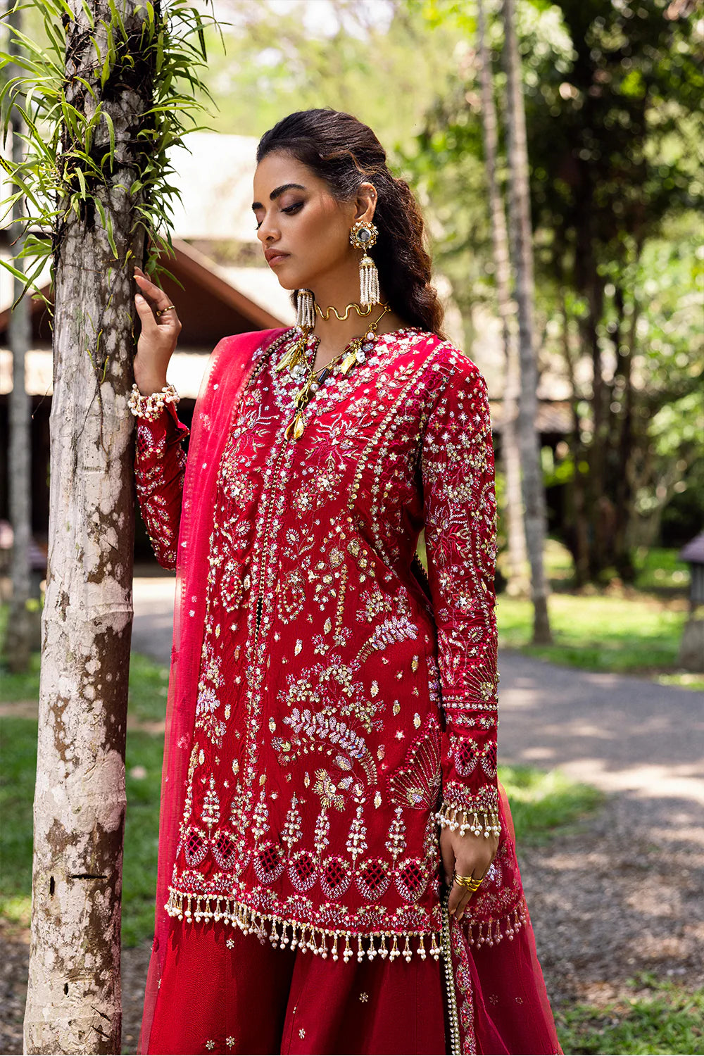 Model wearing Saira Rizwan GOLNAR-SRF25-01 in deep red with gold embellishments – Pakistani luxury pret, shop online in UK.