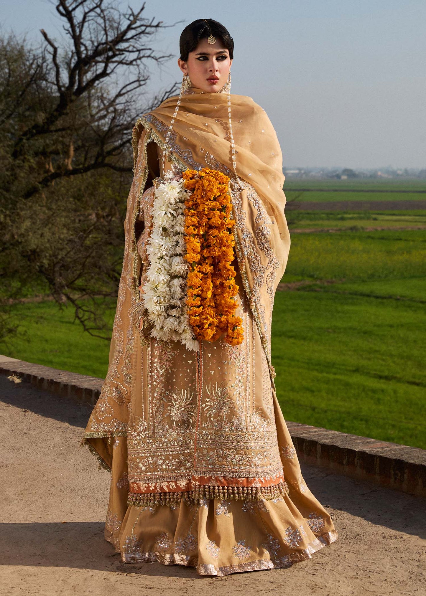 Model wearing Hussain Rehar Sundal golden beige embroidered festive dress with intricate embellishments and traditional details. Shop Pakistani clothes online in the UK now.