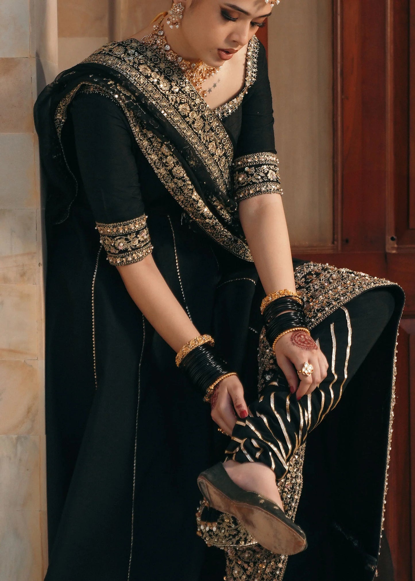 Model wearing Kajal by Kanwal Malik in black with gold embroidery and sheer dupatta – striking Pakistani luxury pret outfit in UK.