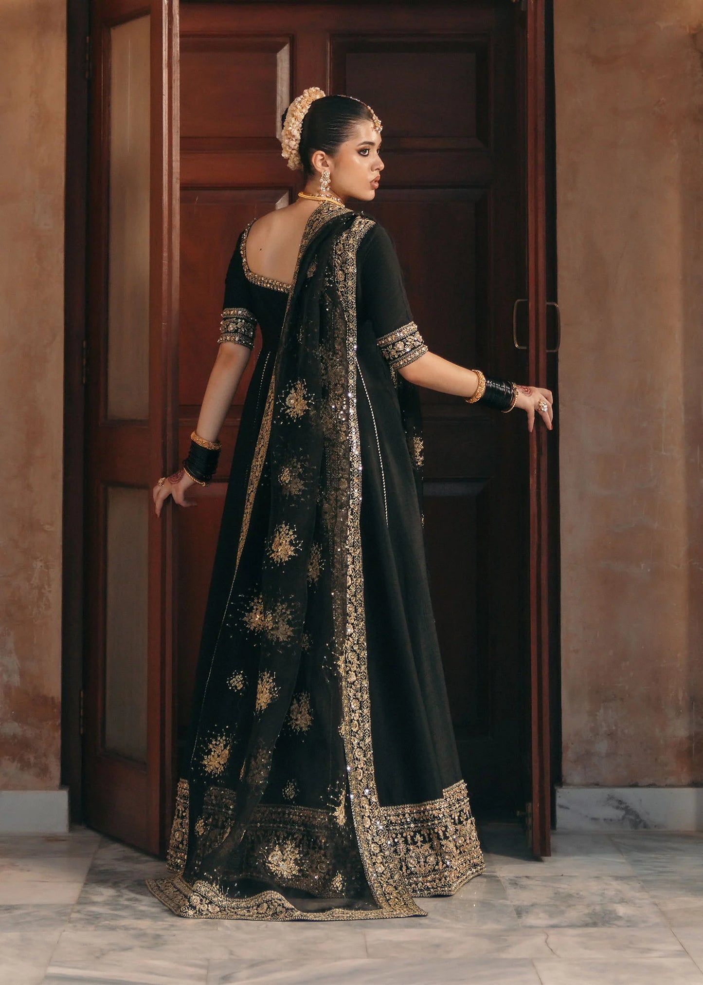 Model wearing Kajal by Kanwal Malik in black with gold embroidery and sheer dupatta – striking Pakistani luxury pret outfit in UK.