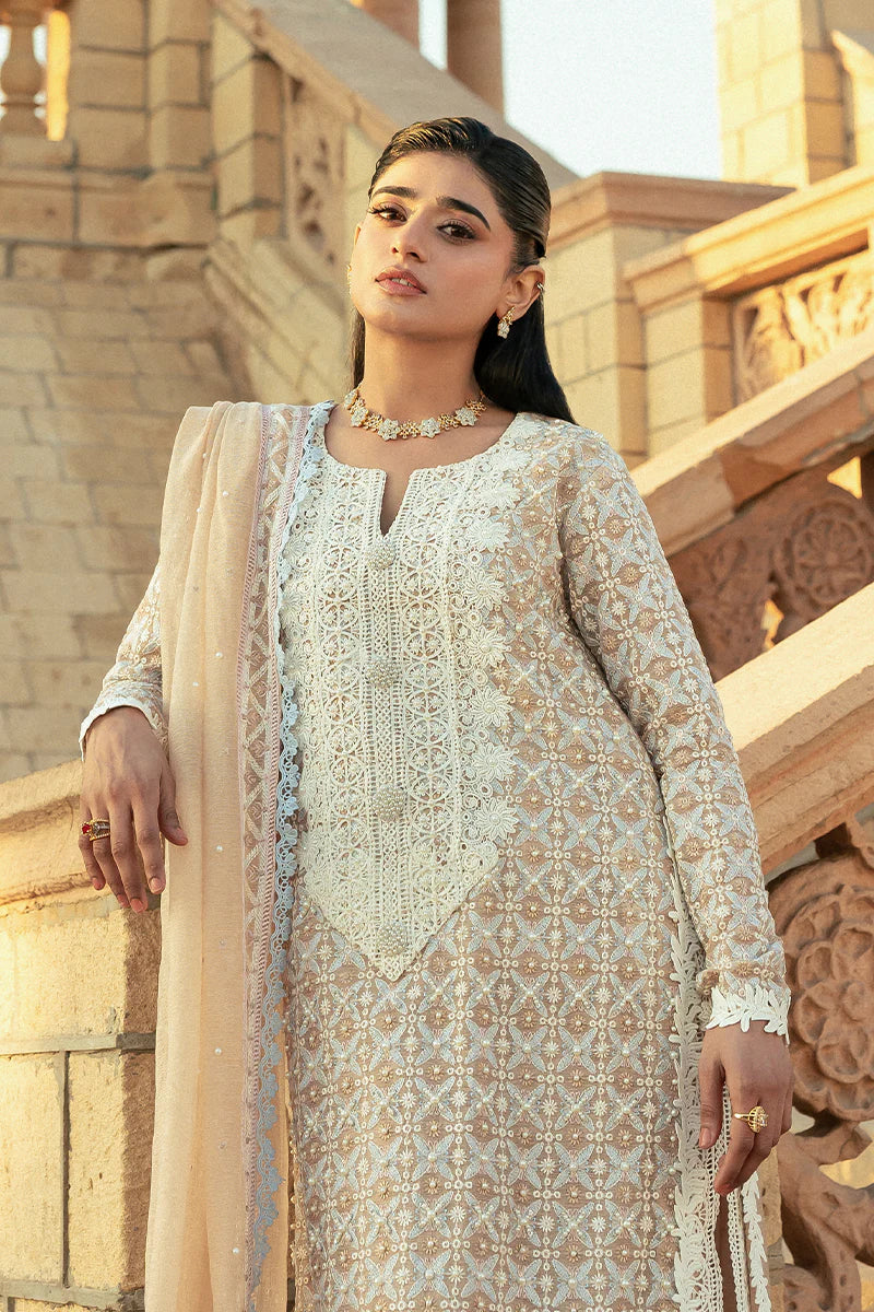 Model wearing Mushq Saugaat City of Lights Faria in beige with intricate embroidery. Shop Pakistani luxury pret online in the UK.