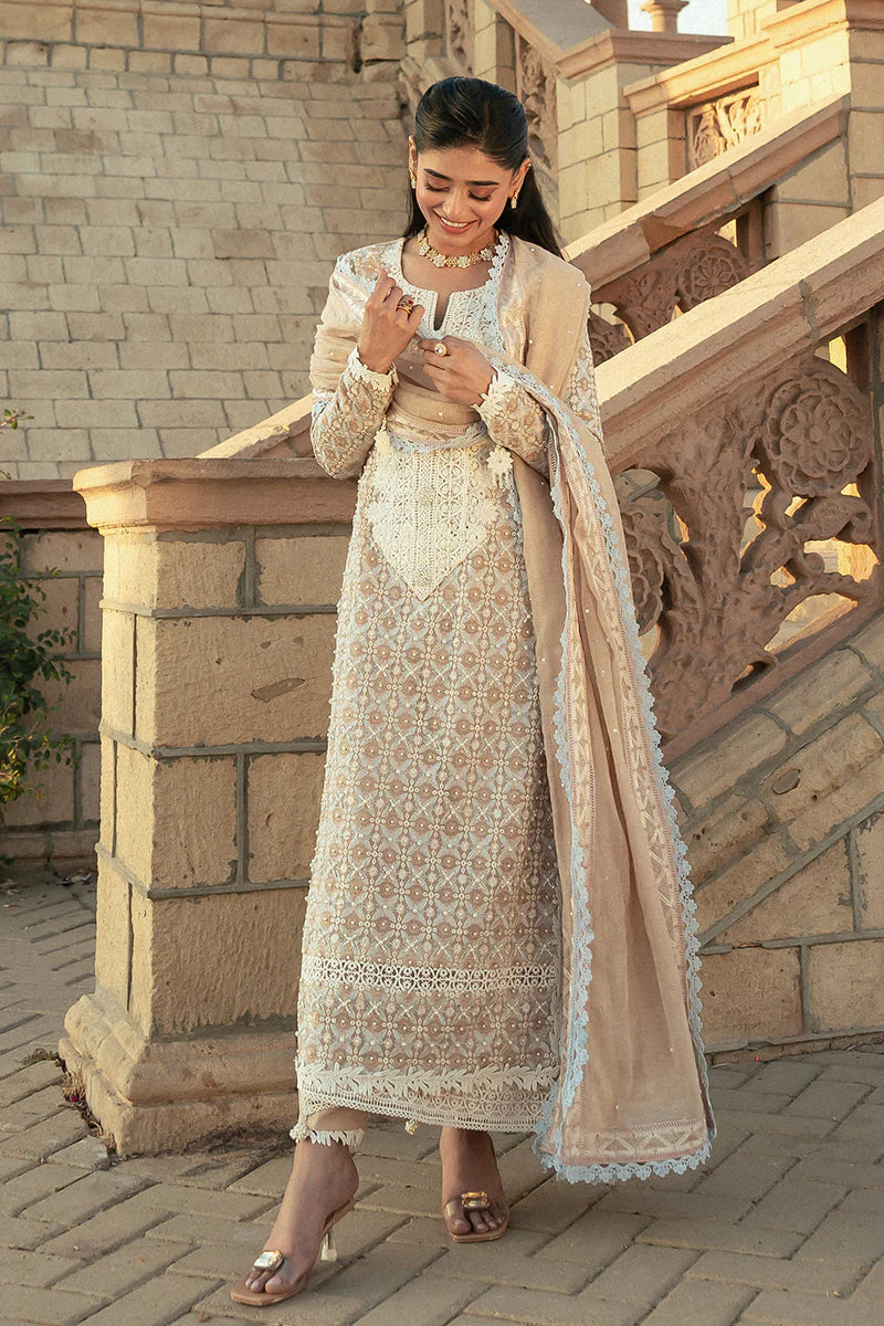 Model wearing Mushq Saugaat City of Lights Faria in beige with intricate embroidery. Shop Pakistani luxury pret online in the UK.