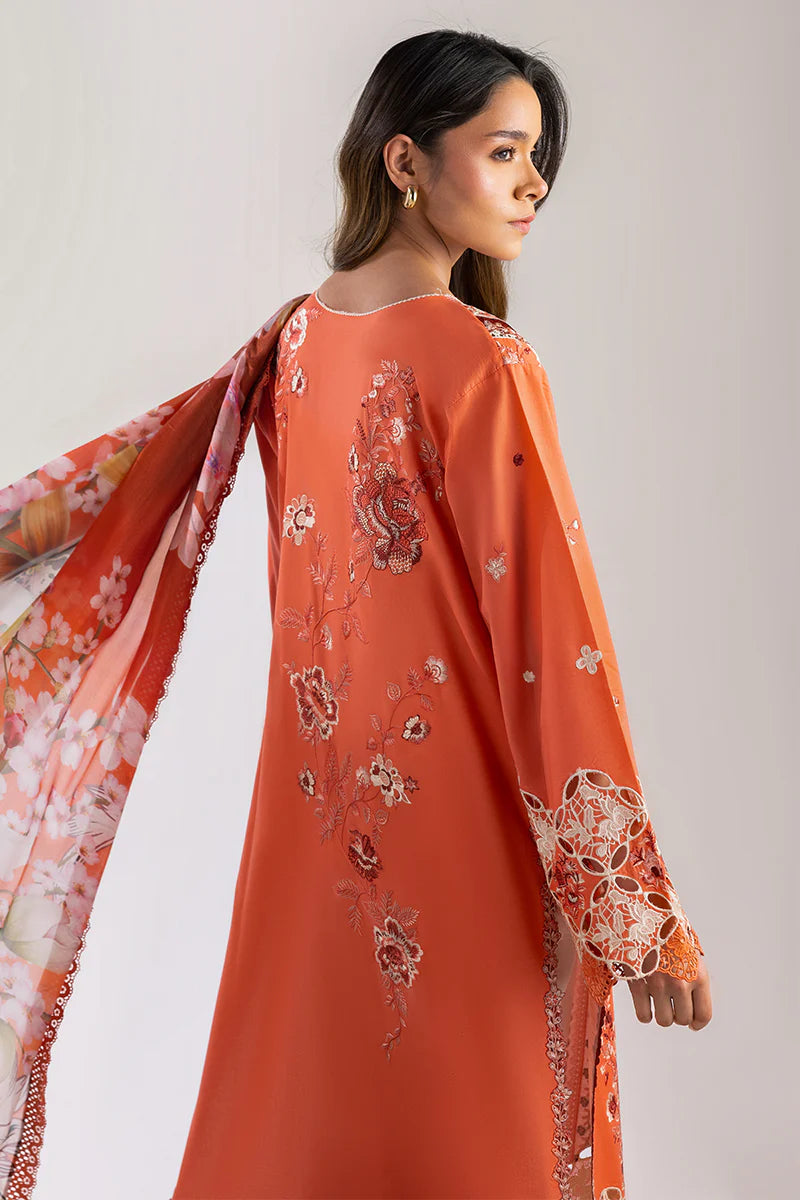 Model wearing burnt orange embroidered dress from Mushq Manaram Luxury Lawn '25 Starry Side, Pakistani luxury pret available online in UK.