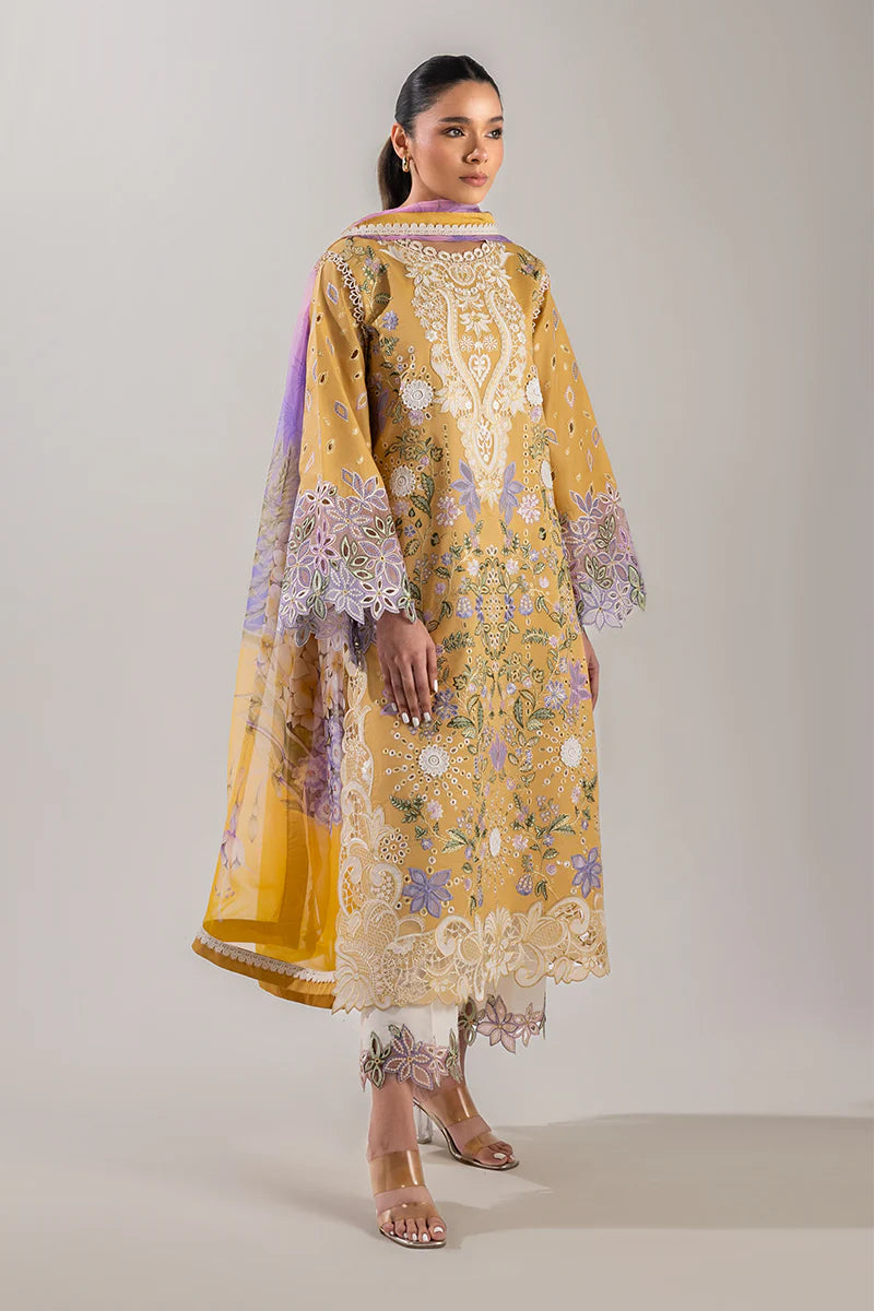 Model wearing mustard yellow embroidered floral shirt with lavender accents from Mushq Manaram Luxury Lawn 2025 Gold Glow. Pakistani clothes online UK.
