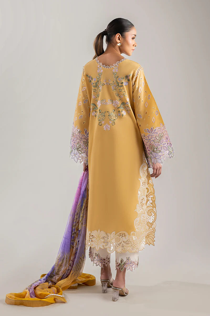 Model wearing mustard yellow embroidered floral shirt with lavender accents from Mushq Manaram Luxury Lawn 2025 Gold Glow. Pakistani clothes online UK.