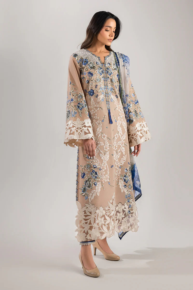 Model wearing beige and blue floral embroidered dress from Mushq Manaram Luxury Lawn '25 Glistening Groove, Pakistani clothes online in UK.