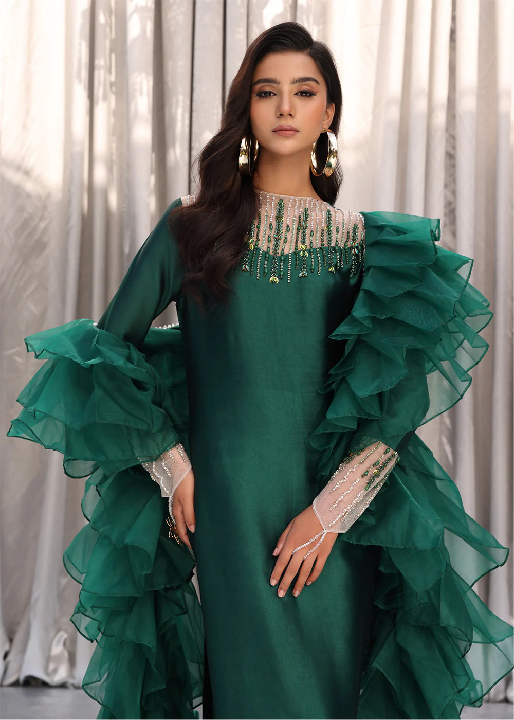 Model wearing emerald green dress with ruffled sleeves and embellished neckline from Musferah Saad Emerald Chic, Pakistani Luxury pret in UK.