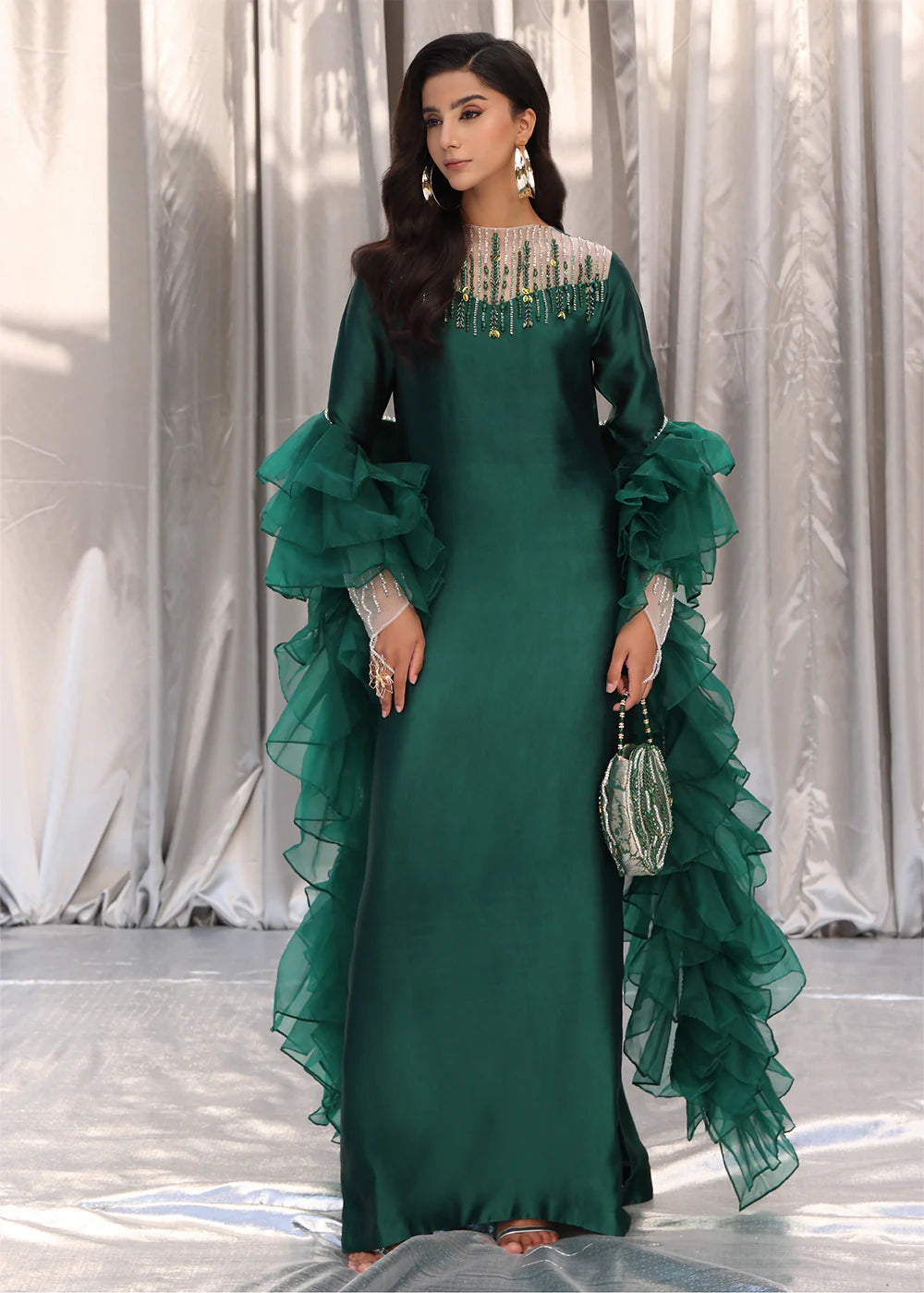 Model wearing emerald green dress with ruffled sleeves and embellished neckline from Musferah Saad Emerald Chic, Pakistani Luxury pret in UK.