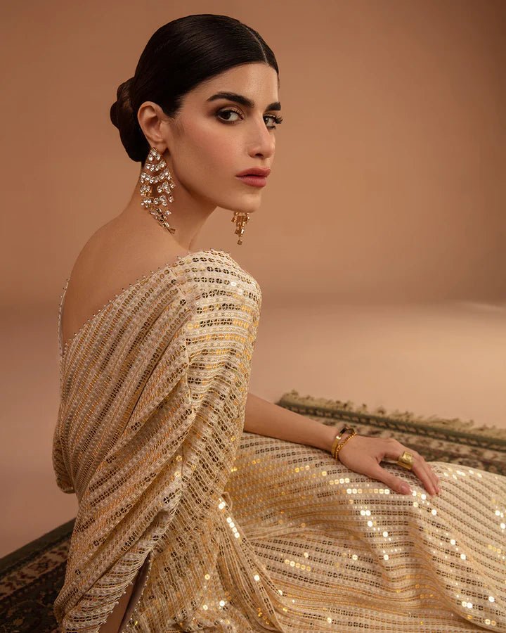Model wearing a gold Beyza dress from Faiza Saqlain's Aleira Evening Edit '24 collection. Pakistani clothes online in UK.