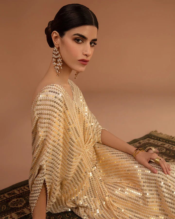 Model wearing a gold Beyza dress from Faiza Saqlain's Aleira Evening Edit '24 collection. Pakistani clothes online in UK.