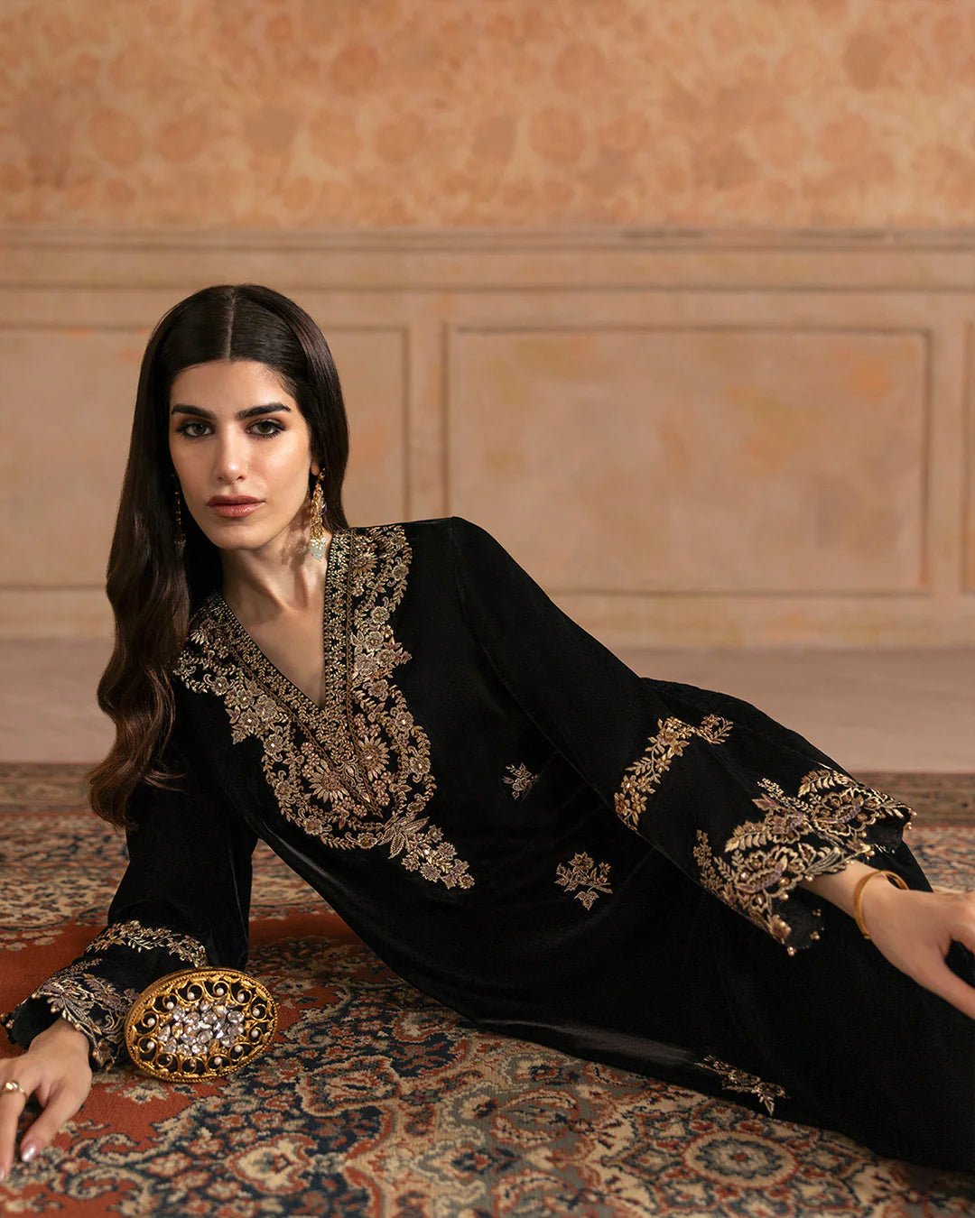 Model wearing Faiza Saqlain Ismene Velvet Vita dress in black with luxurious gold embroidery. Shop Pakistani bridal dresses online in the UK now.