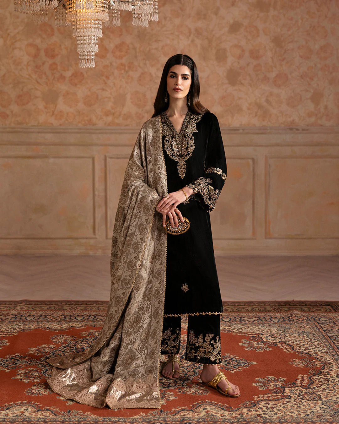 Model wearing Faiza Saqlain Ismene Velvet Vita dress in black with luxurious gold embroidery. Shop Pakistani bridal dresses online in the UK now.