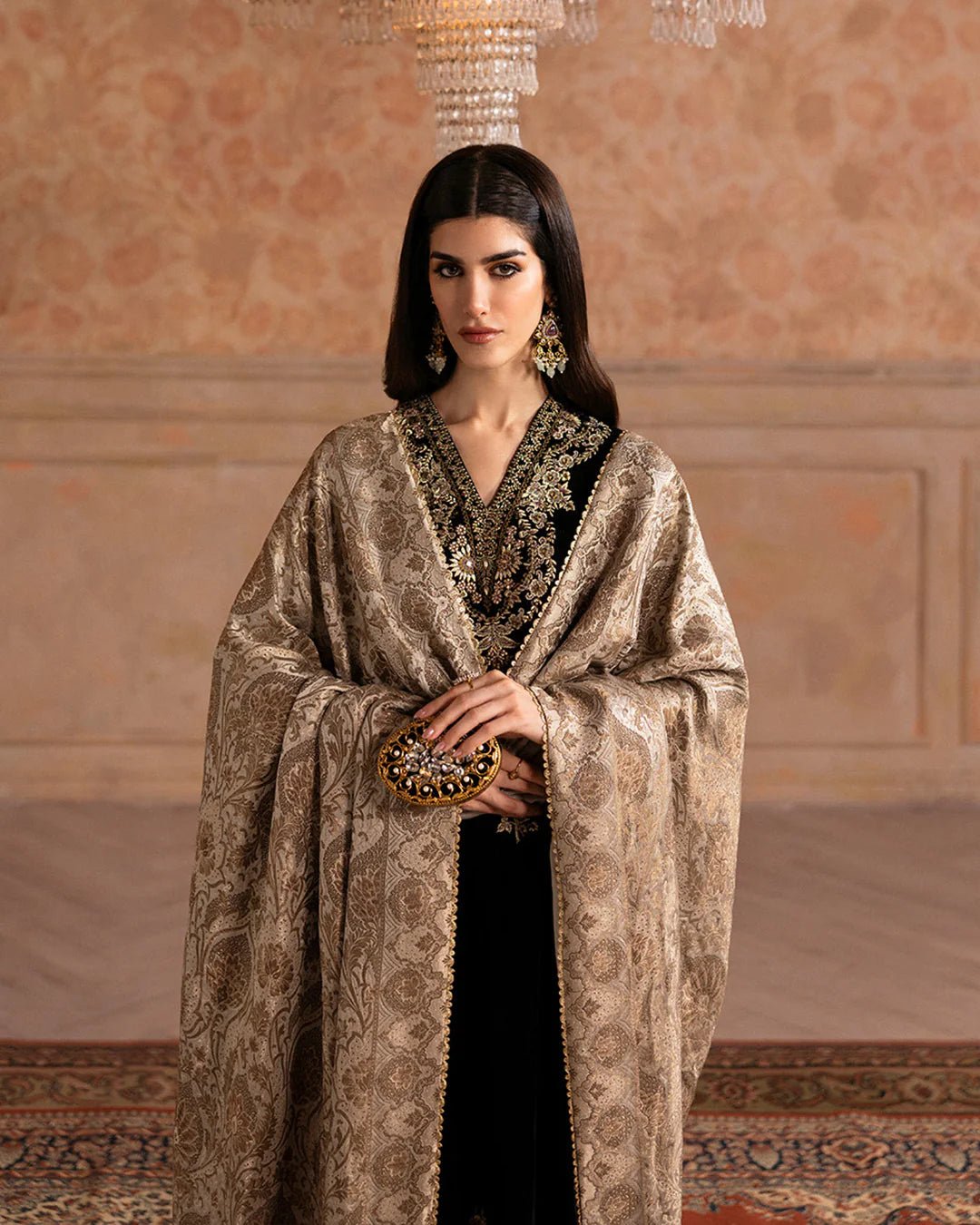 Model wearing Faiza Saqlain Ismene Velvet Vita dress in black with luxurious gold embroidery. Shop Pakistani bridal dresses online in the UK now.