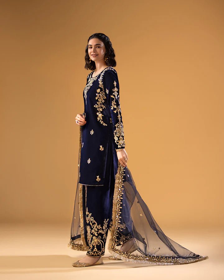 Model wearing a navy blue Sayonee dress with gold embroidery from Faiza Saqlain'sMakhmal collection. Pakistani clothes online in UK.