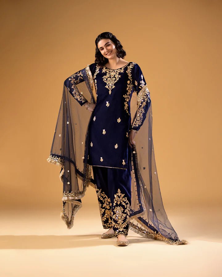 Model wearing a navy blue Sayonee dress with gold embroidery from Faiza Saqlain'sMakhmal collection. Pakistani clothes online in UK.