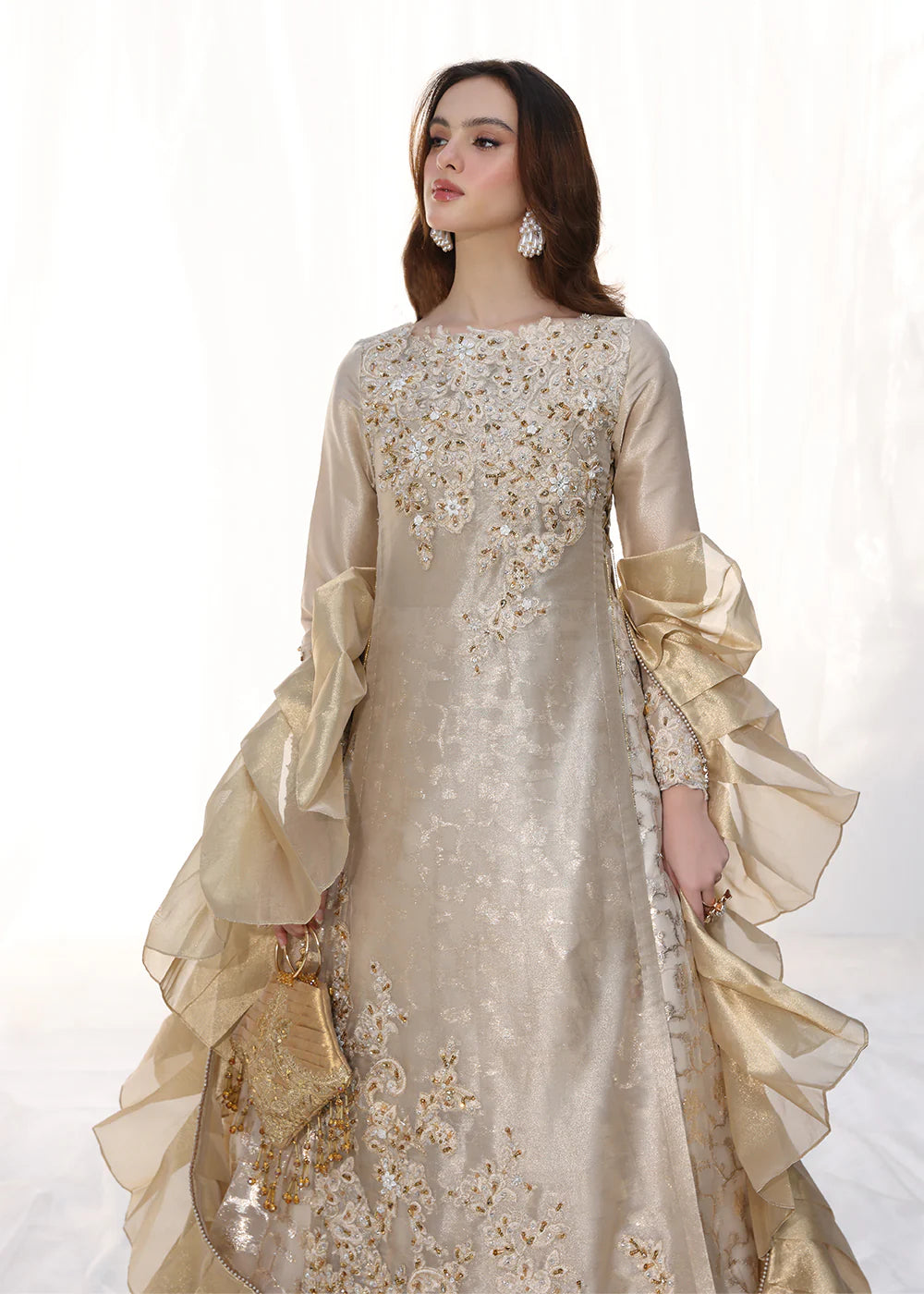 Model wearing gold embellished long dress with ruffled sleeves from Musferah Saad Golden Whispers, Pakistani Luxury pret in UK.