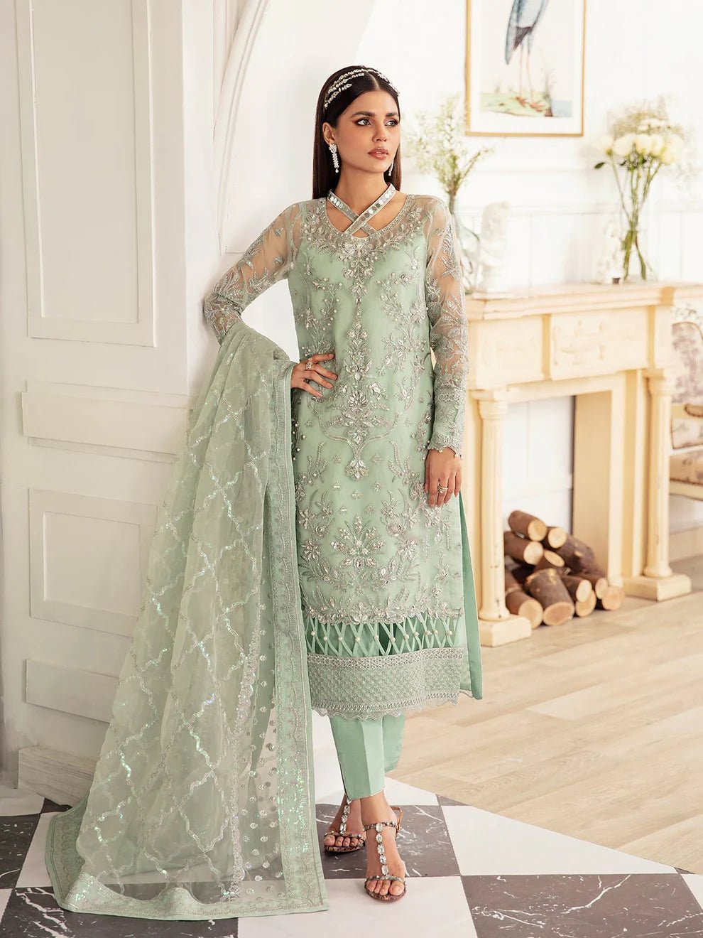 Model wearing a mint green embroidered dress, featuring intricate silver detailing and sheer sleeves from Gulaal. Ideal for showcasing Gulaal's luxury pret collection and Pakistani clothes online in the UK.
