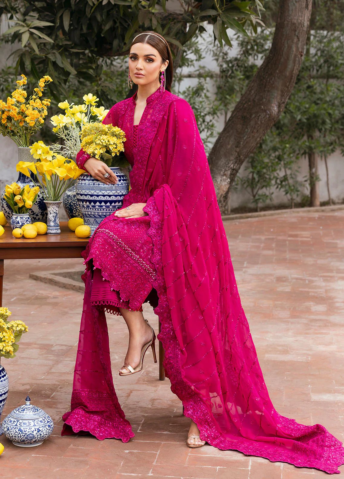 Model wearing Gulaal Zevira hot pink embroidered chiffon dress with matching dupatta and trousers. Shop Pakistani clothes online in the UK now.