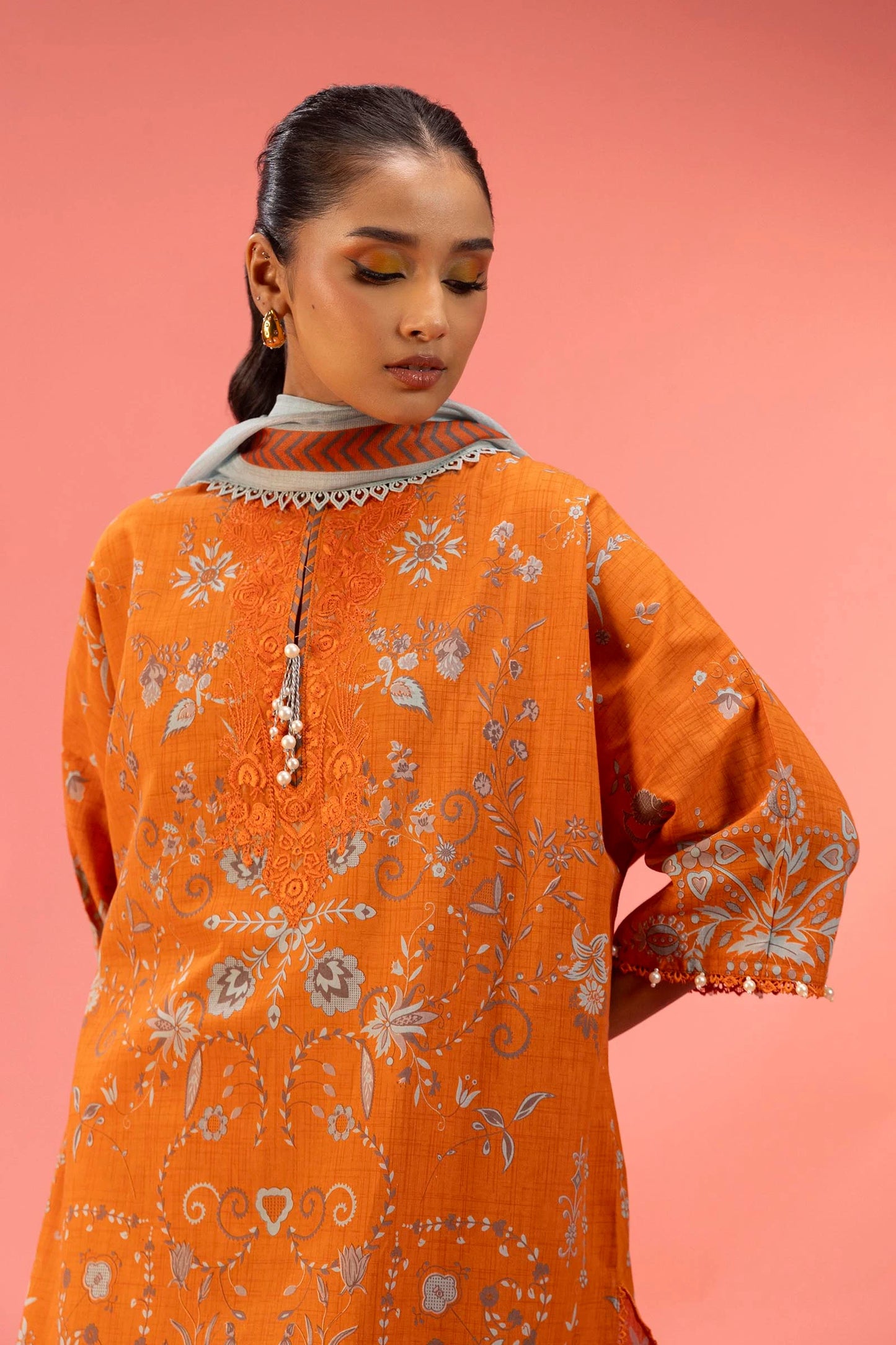 Model wearing bright orange embroidered outfit with light grey dupatta from Sana Safinaz, Mahay Spring '25, Pakistani casual pret in UK.