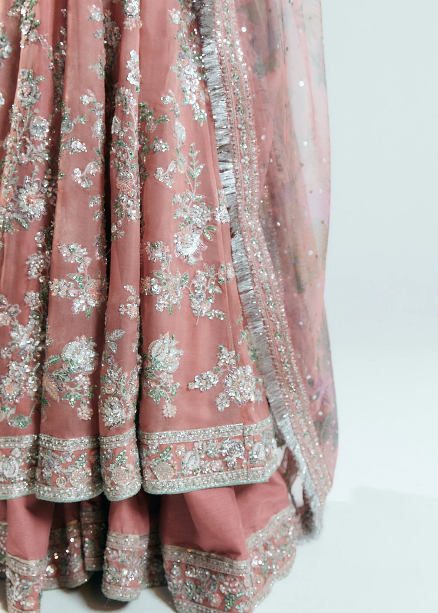 Model wearing Hussain Rehar Sitaray Formals Tropica, a peach - colored dress with intricate silver embroidery and embellishments, ideal for weddings.