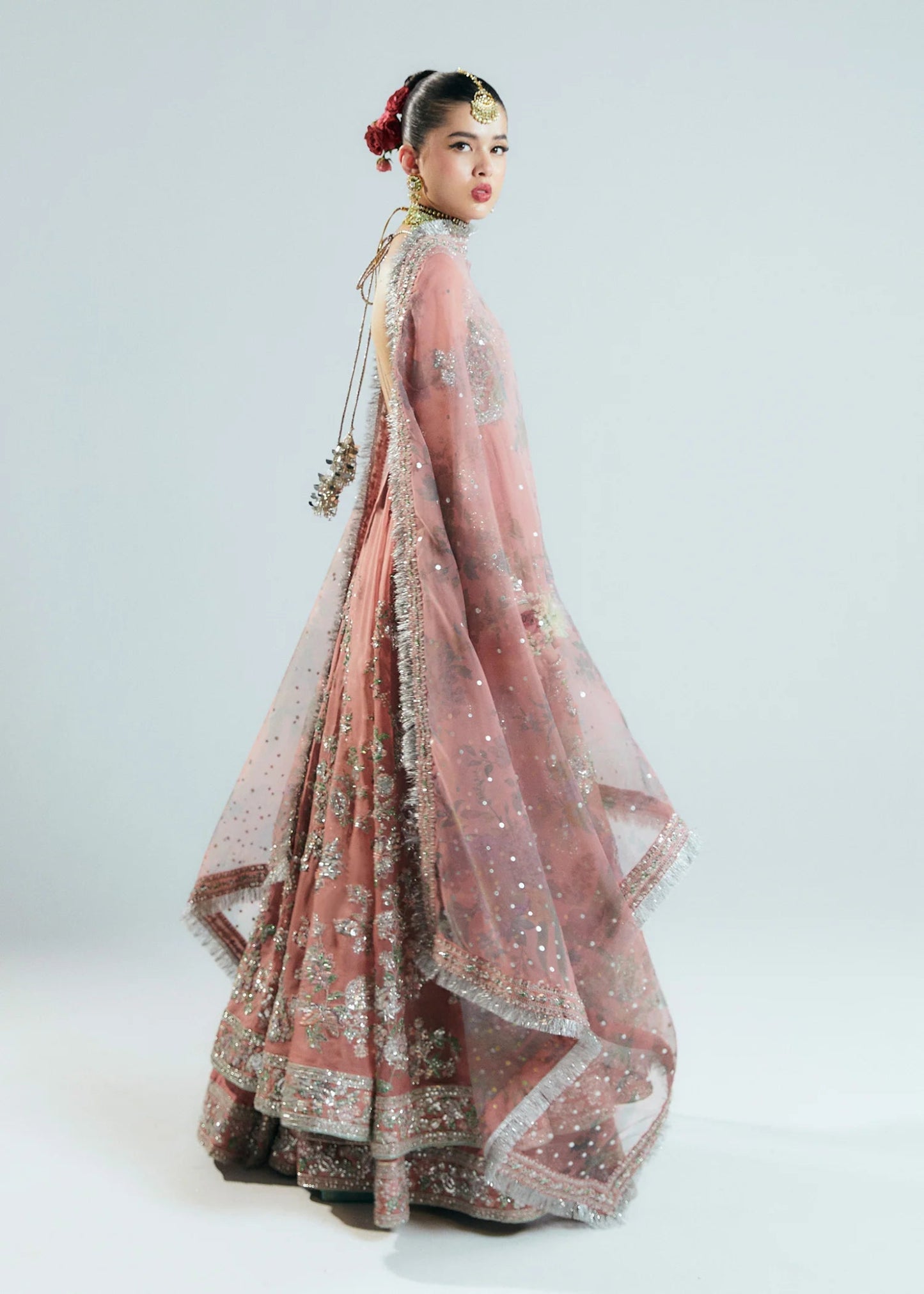 Model wearing Hussain Rehar Sitaray Formals Tropica, a peach - colored dress with intricate silver embroidery and embellishments, ideal for weddings.
