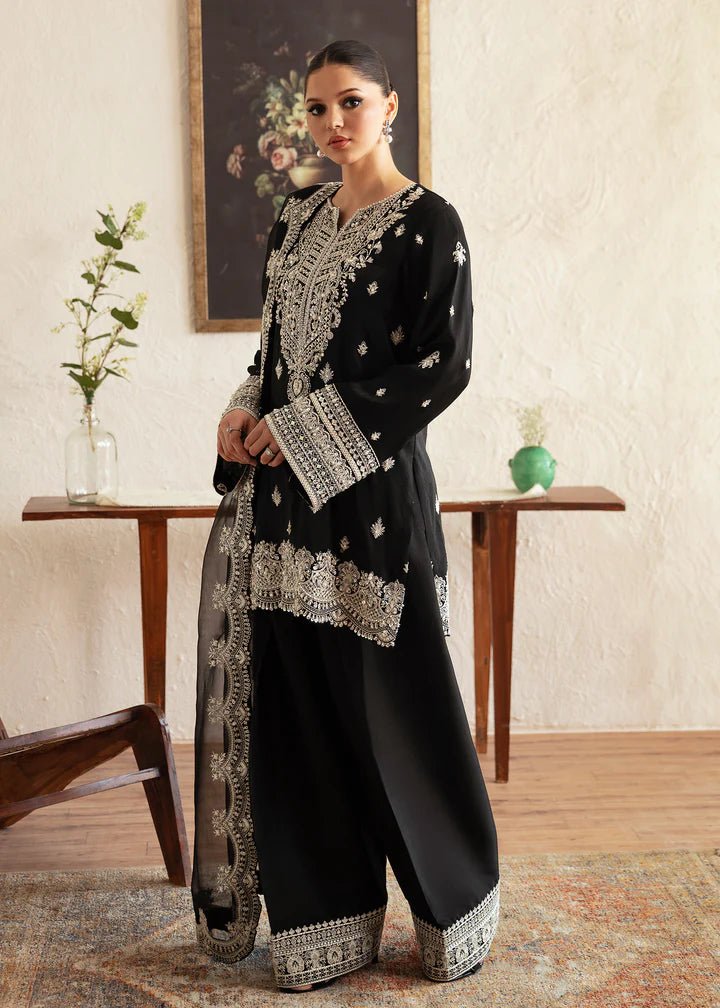 Model wearing a black Soha dress from Kanwal Malik's Amelie Luxury Pret collection. The outfit features intricate silver embroidery. Perfect for Pakistani clothes online in the UK, especially for wedding clothes and festive occasions.