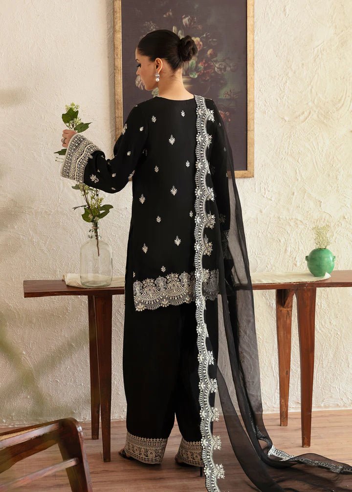 Model wearing a black Soha dress from Kanwal Malik's Amelie Luxury Pret collection. The outfit features intricate silver embroidery. Perfect for Pakistani clothes online in the UK, especially for wedding clothes and festive occasions.