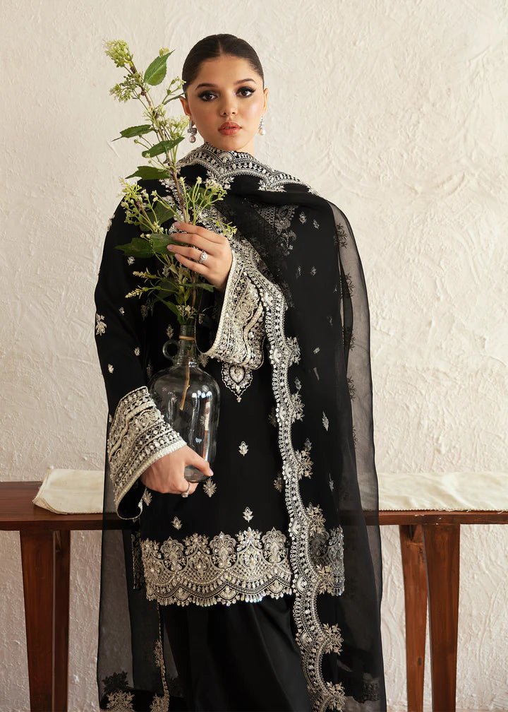 Model wearing a black Soha dress from Kanwal Malik's Amelie Luxury Pret collection. The outfit features intricate silver embroidery. Perfect for Pakistani clothes online in the UK, especially for wedding clothes and festive occasions.