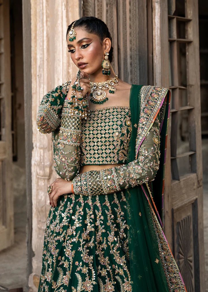Model wearing a rich emerald green Sukhan lehenga from Kanwal Malik's Sajni II collection, embellished with intricate gold embroidery. Pakistani wedding clothes online in the UK.