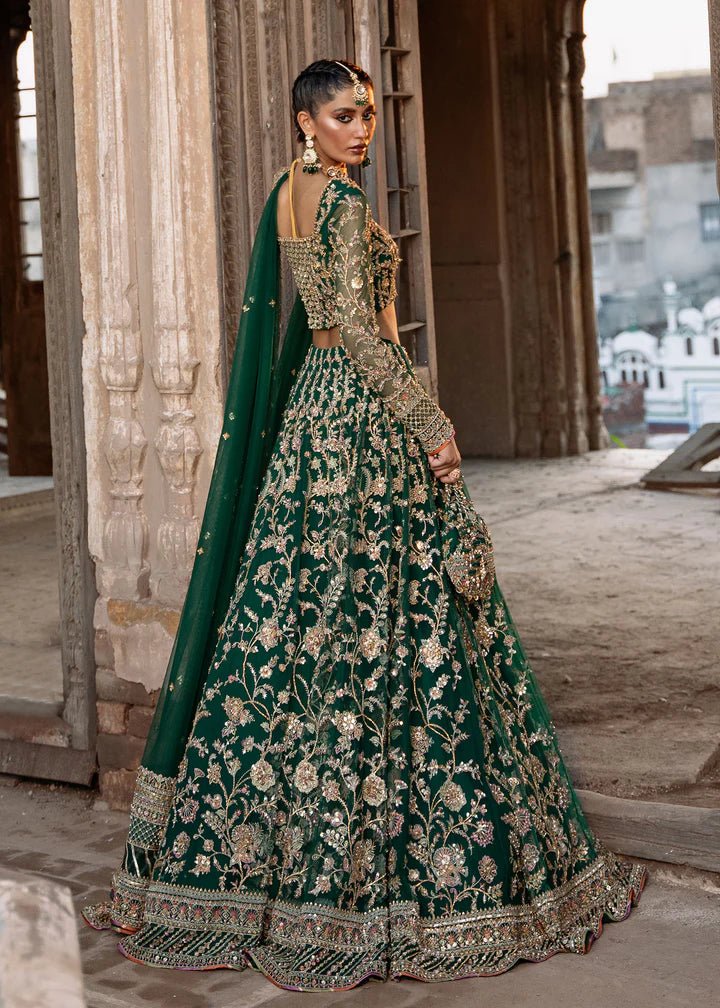 Model wearing a rich emerald green Sukhan lehenga from Kanwal Malik's Sajni II collection, embellished with intricate gold embroidery. Pakistani wedding clothes online in the UK.