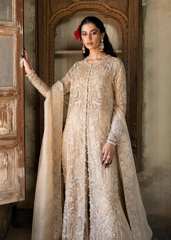 Model wearing an ivory - colored Zarnab dress from Kanwal Malik's Sajni II Formal Collection, adorned with intricate embellishments. Pakistani wedding clothes available online in the UK.