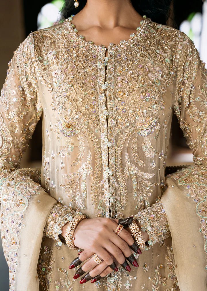 Model wearing an ivory - colored Zarnab dress from Kanwal Malik's Sajni II Formal Collection, adorned with intricate embellishments. Pakistani wedding clothes available online in the UK.