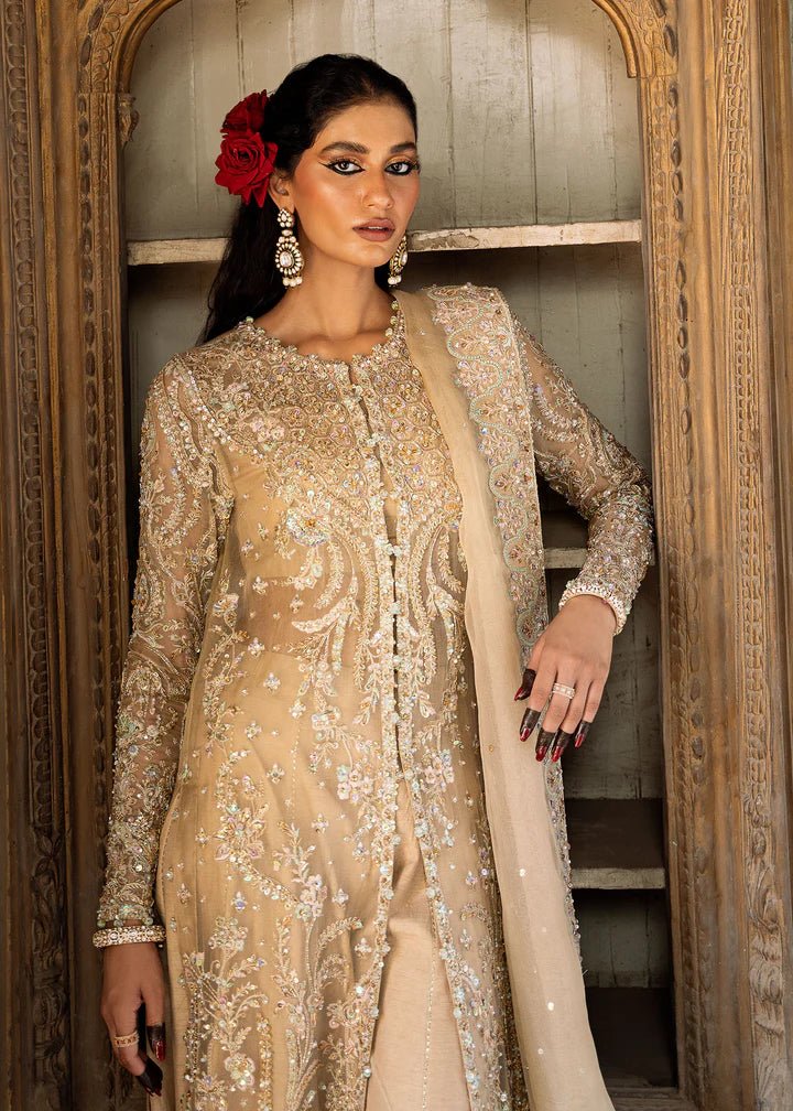 Model wearing an ivory - colored Zarnab dress from Kanwal Malik's Sajni II Formal Collection, adorned with intricate embellishments. Pakistani wedding clothes available online in the UK.