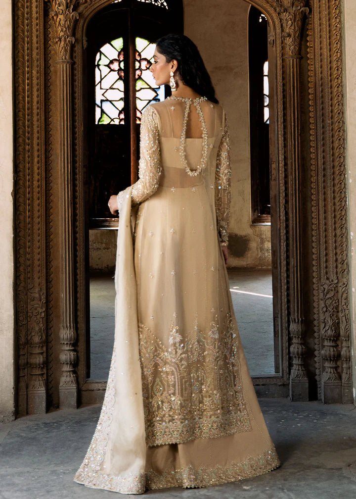 Model wearing an ivory - colored Zarnab dress from Kanwal Malik's Sajni II Formal Collection, adorned with intricate embellishments. Pakistani wedding clothes available online in the UK.