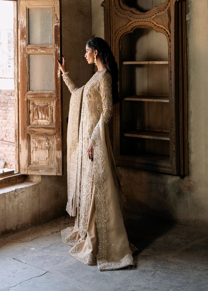 Model wearing an ivory - colored Zarnab dress from Kanwal Malik's Sajni II Formal Collection, adorned with intricate embellishments. Pakistani wedding clothes available online in the UK.