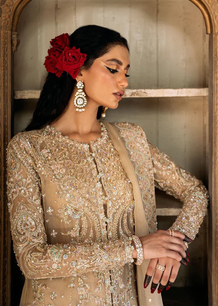 Model wearing an ivory - colored Zarnab dress from Kanwal Malik's Sajni II Formal Collection, adorned with intricate embellishments. Pakistani wedding clothes available online in the UK.